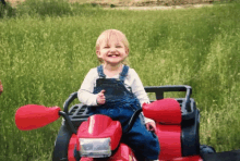 a little girl is sitting on a red atv in the grass