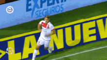 a soccer player is running in front of a sign that says la nuevo