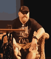 a man with a beard wearing a hat that says ' ny ' on it sits in a chair