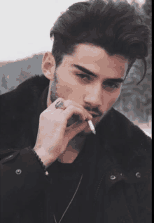 a man in a black jacket is smoking a cigarette