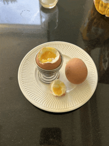 a hard boiled egg sits on a white plate next to a half hard boiled egg