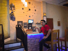 a man sits at a bar with a clock on the wall that says ' coffee shop ' on it