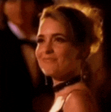 a close up of a woman wearing a choker and earrings smiling .