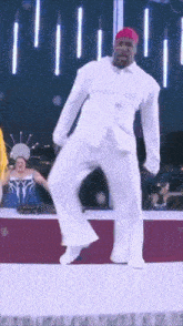 a man in a white shirt and white pants is dancing on a stage