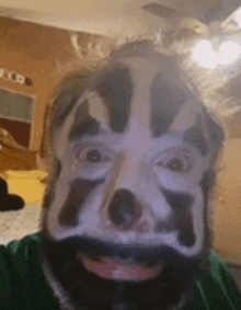 a man with a beard and clown makeup on his face is taking a selfie .