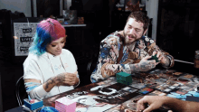 a man and a woman are playing a board game with a sign that says " black lives matter " in the background