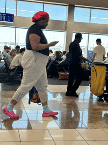 a woman wearing pink crocs and socks walking in an airport