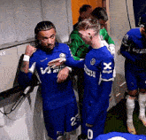 a group of soccer players are standing in a locker room and one of them has the number 0 on his shorts