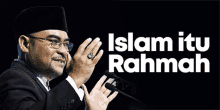 a man in a suit speaking into a microphone with the words islam itu rahman below him