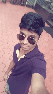 a young man wearing sunglasses and a purple shirt is taking a selfie