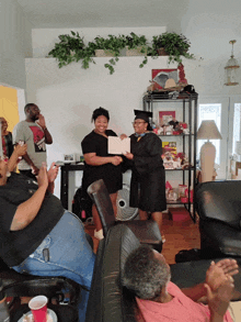 a woman in a cap and gown is holding a certificate