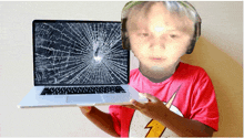 a young boy holding a laptop with a broken screen