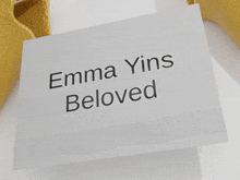 a card that says emma yins beloved sits on a white surface