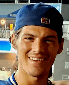 a man wearing a blue hat is smiling in front of a sign that says tap