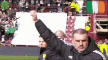 a man holds up his fist in the air in front of a scoreboard that says cel 1 on it