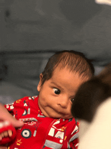 a baby wearing a red fire truck pajama looks at the camera