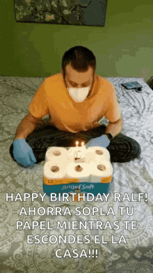 a man wearing a mask and gloves is sitting on a bed with a box of angel soft toilet paper