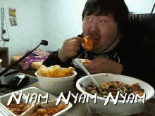 a man is sitting at a table with bowls of food and the words nyam nyam nyam