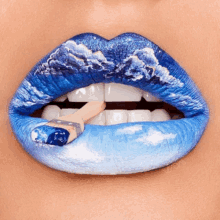 a close up of a woman 's mouth with blue lipstick and a brush with blue paint on it