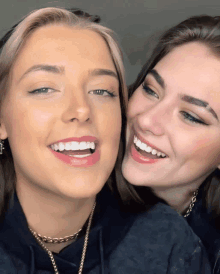 two young women are smiling for the camera and one has a necklace around her neck