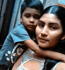 a woman is holding a young boy who is wearing a shirt with paw prints