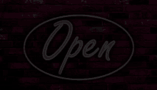 a brick wall with a black sign that says open