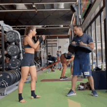 a man and a woman are boxing in a gym with a man wearing a shirt that says ' nb '