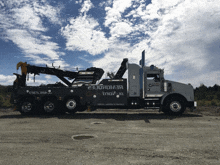 a tow truck is parked in a gravel lot with a blue sky behind it