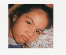 a young girl laying on a bed with a floral comforter