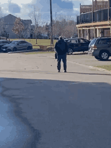 a man wearing a mask walks down a parking lot