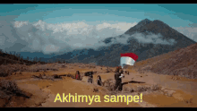 a group of people standing on top of a mountain holding a flag with the words " akhirnya sampe " below them