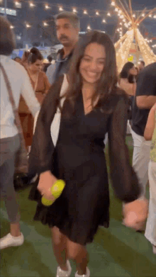 a woman in a black dress is dancing in front of a crowd