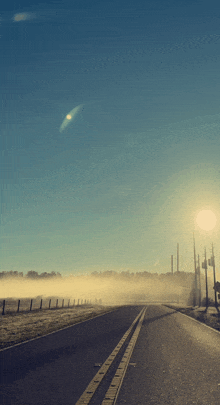 a foggy road with the sun shining brightly on it