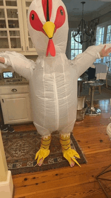 a person in an inflatable chicken costume is standing in a kitchen