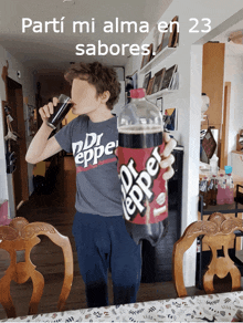 a boy in a dr pepper shirt drinks from a glass while holding a bottle