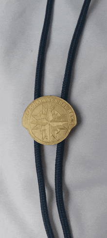 a gold coin on a black string that says gobernadores del mar