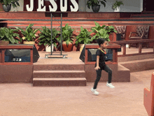 a little girl is running in front of a large sign that says jesus