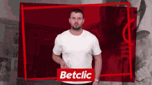 a man in a white shirt is standing in front of a betclic sign