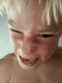 a young boy without a shirt is making a funny face with his mouth open