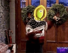 a person in a sweater is holding a wreath in front of a door that says texture on it