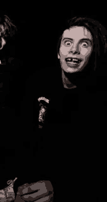 a young man with a missing tooth is making a funny face in the dark .