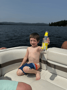 a young boy is sitting on a boat holding a bottle of corona beer