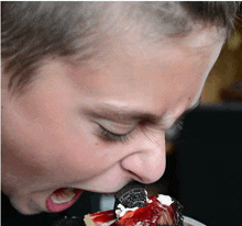 a young boy is eating a strawberry cheesecake with a oreo cookie in his mouth