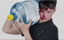 a man in a black shirt is carrying a large water bottle on his shoulder