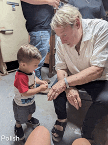 a little boy in a red white and blue shirt is standing next to a man in a white shirt