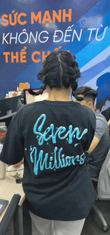 a woman wearing a black shirt that says seven millions on the back