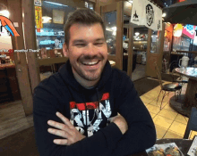 a man sitting at a table with his arms crossed wearing a shirt that says ' nln ' on it