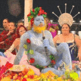 a man with blue body paint is holding a microphone in front of a group of women