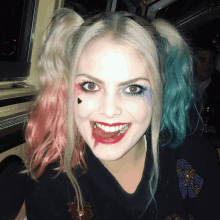 a woman in a harley quinn costume is smiling with her tongue out