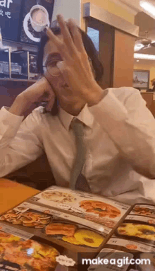 a man in a white shirt and tie is sitting at a table in front of a menu